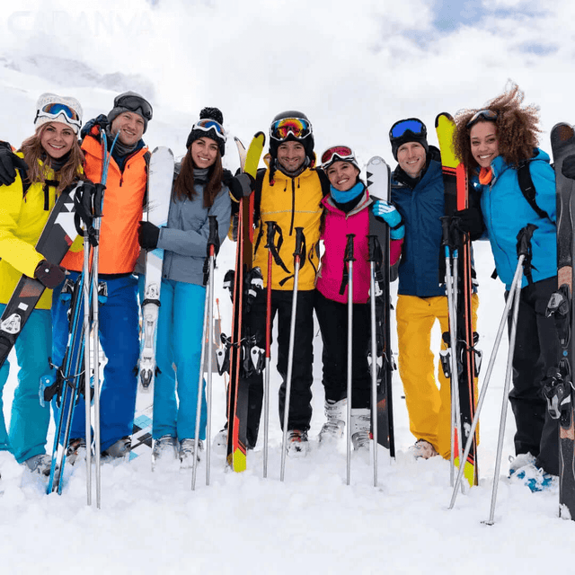 Groep vrienden lacht in de sneeuw met hun ski’s en stokken